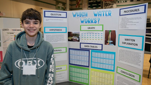 student in front of Science Fair project board